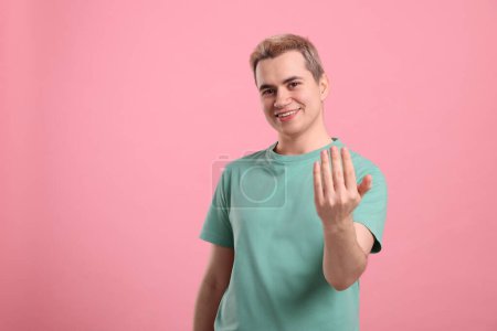 Téléchargez les photos : Happy man inviting to come in against pink background, space for text - en image libre de droit