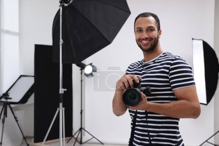 Téléchargez les photos : Jeune photographe professionnel avec appareil photo dans un studio photo moderne, espace pour le texte - en image libre de droit