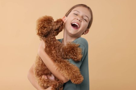 Emotional little child with cute puppy on beige background. Lovely pet