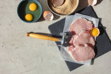 Téléchargez les photos : Schnitzel de cuisine. Côtelettes de porc crues, maillet de viande et ingrédients sur table grise, plat avec espace pour le texte - en image libre de droit