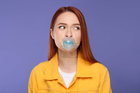 Photo for Beautiful woman blowing bubble gum on purple background - Royalty Free Image