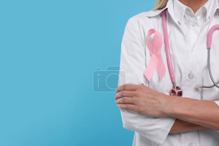 Téléchargez les photos : Docteur avec ruban rose et stéthoscope sur fond bleu clair, gros plan et espace pour le texte. Sensibilisation au cancer du sein - en image libre de droit