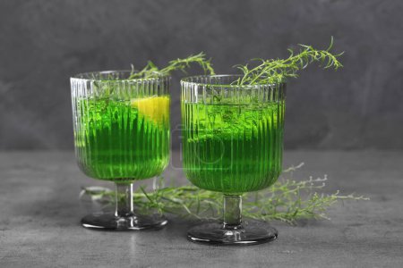 Photo for Glasses of homemade refreshing tarragon drink and sprigs on grey table - Royalty Free Image