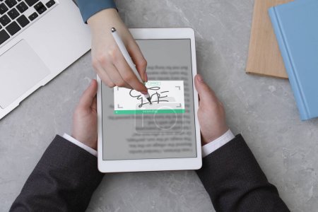 Electronic signature. Woman using stylus and tablet at table, top view