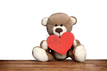 Photo for Cute teddy bear with red heart on wooden table against white background - Royalty Free Image