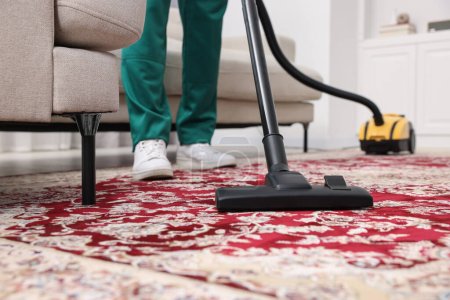 Photo for Dry cleaner's employee hoovering carpet with vacuum cleaner indoors, selective focus - Royalty Free Image