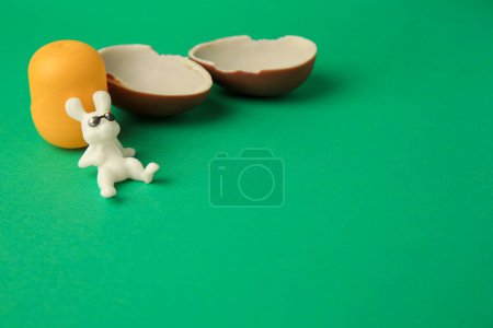 Photo for Slynchev Bryag, Bulgaria - May 25, 2023: Halves of Kinder Surprise Egg, plastic capsule and toy bunny on green background, space for text - Royalty Free Image