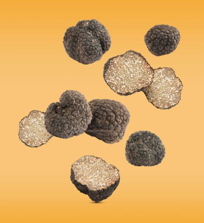 Photo for Cut and whole truffles falling on golden background - Royalty Free Image