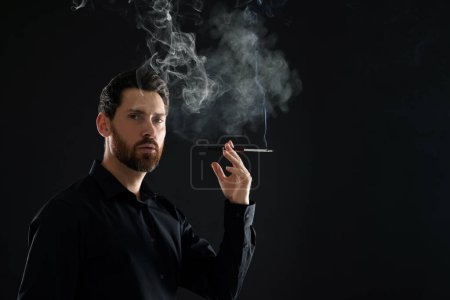 Man using cigarette holder for smoking on black background, space for text