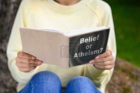 Téléchargez les photos : Femme lisant un livre sur la croyance et l'athéisme à l'extérieur, gros plan - en image libre de droit