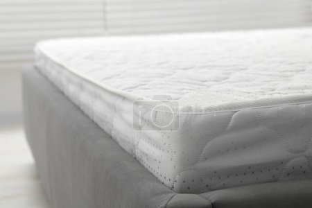Nuevo colchón verde claro en cama gris en el interior, primer plano. Espacio para texto