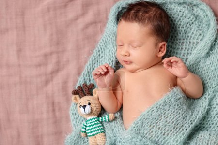 Photo for Cute newborn baby with toy deer in turquoise blanket sleeping on bed, top view. Space for text - Royalty Free Image