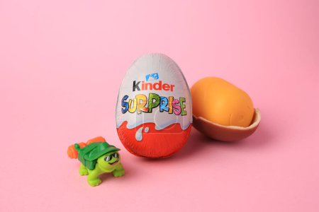 Slynchev Bryag, Bulgaria - May 25, 2023: Kinder Surprise Eggs, plastic capsule and toy turtle on pink background