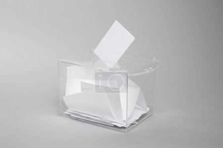 Foto de Caja de votación con votos sobre fondo gris claro. Tiempo de elección - Imagen libre de derechos