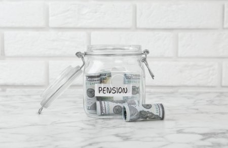 Téléchargez les photos : Pot en verre avec mot Pension et billets sur table en marbre blanc - en image libre de droit