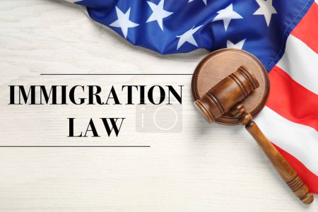 Einwanderungsgesetz. Richtergabel und amerikanische Flagge auf weißem Holztisch, Draufsicht