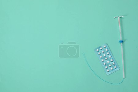 Photo for Contraception choice. Pills and intrauterine device on turquoise background, flat lay. Space for text - Royalty Free Image