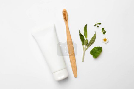 Téléchargez les photos : Brosse à dents en bambou, tube de crème et d'herbes sur fond blanc, plat - en image libre de droit