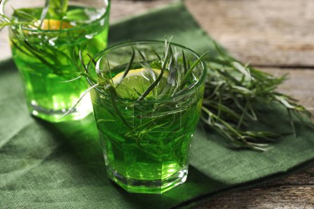 Photo for Glasses of refreshing tarragon drink with lemon slices on wooden table, closeup - Royalty Free Image