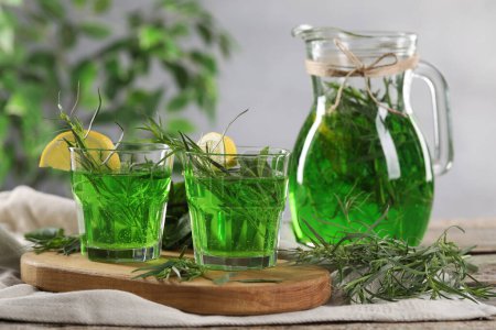Photo for Glasses and jug of refreshing tarragon drink with lemon slices on table - Royalty Free Image