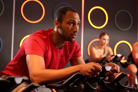 Foto de Grupo de personas entrenando en bicicletas estáticas en el gimnasio - Imagen libre de derechos
