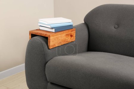 Photo for Books on sofa with wooden armrest table in room. Interior element - Royalty Free Image