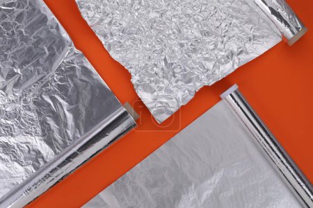 Photo for Different rolls of aluminum foil on orange background, flat lay - Royalty Free Image