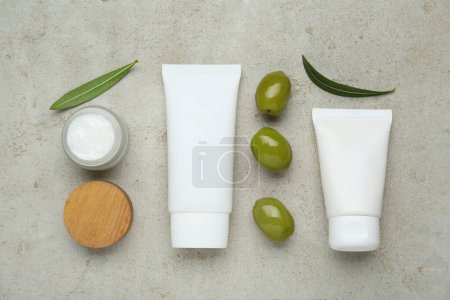 Téléchargez les photos : Produits cosmétiques à l'huile essentielle d'olive sur table gris clair, pose plate - en image libre de droit