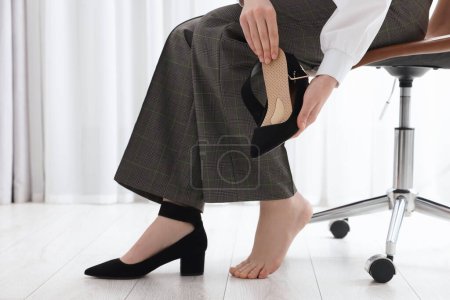 Foto de Mujer poniendo plantilla ortopédica en zapato de tacón alto en el interior, primer plano. Cuidado de los pies - Imagen libre de derechos