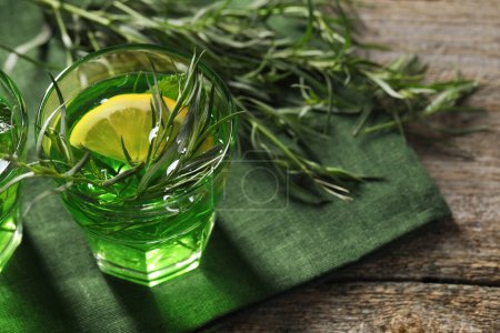 Photo for Glass of refreshing tarragon drink with lemon slice on wooden table. Space for text - Royalty Free Image