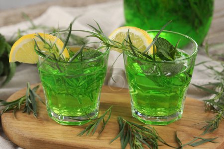 Photo for Glasses of refreshing tarragon drink with lemon slices on tablecloth - Royalty Free Image