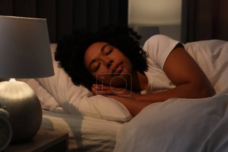 Foto de Mujer joven durmiendo en cama blanda por la noche - Imagen libre de derechos