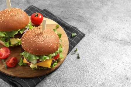 Photo for Delicious burgers with beef patty and tomatoes on grey table. Space for text - Royalty Free Image