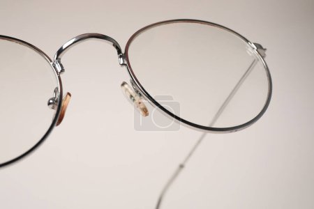 Stylish pair of glasses with metal frame on beige background, closeup