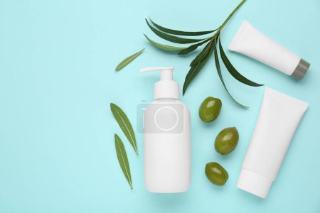Téléchargez les photos : Produits cosmétiques à l'huile essentielle d'olive sur fond turquoise clair, pose plate. Espace pour le texte - en image libre de droit