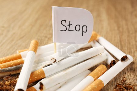 Photo for Pile of cigarettes and flag with word Stop on wooden table, closeup. No smoking concept - Royalty Free Image