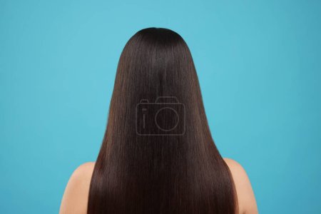 Frau mit gesunden Haaren nach der Behandlung auf hellblauem Hintergrund, Rückseite