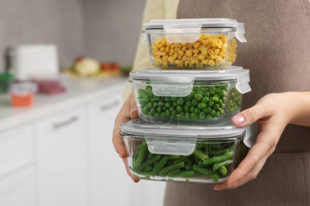 Woman holding containers with different fresh products in kitchen, closeup and space for text. Food storage