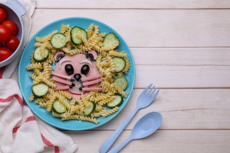 Téléchargez les photos : Service créatif pour les enfants. Assiette avec ours mignon faite de pâtes savoureuses, de légumes et de saucisses sur une table en bois blanc, à plat. Espace pour le texte - en image libre de droit