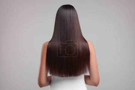 Woman with healthy hair after treatment on light gray background, back view