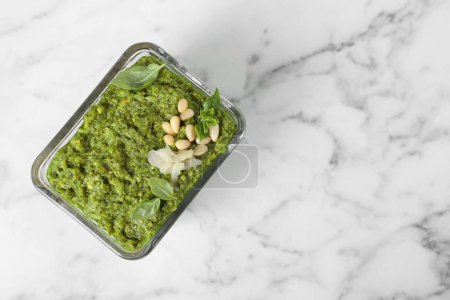 Photo for Delicious pesto sauce in bowl on white marble table, top view. Space for text - Royalty Free Image