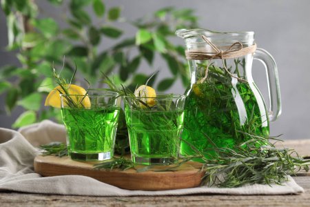 Photo for Glasses and jug of homemade refreshing tarragon drink with lemon slices on table - Royalty Free Image