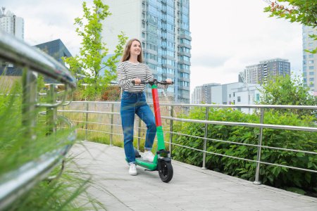 Photo for Happy woman with modern electric kick scooter on city street, space for text - Royalty Free Image