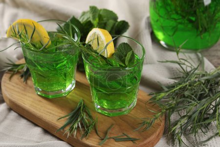 Photo for Glasses of refreshing tarragon drink with lemon slices on tablecloth - Royalty Free Image