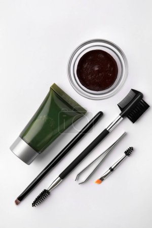 Téléchargez les photos : Composition à plat avec henné des sourcils, outils professionnels et produits cosmétiques sur fond blanc - en image libre de droit
