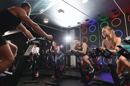 Photo for Group of people training on exercise bikes in fitness club - Royalty Free Image