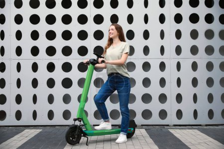 Photo for Happy woman with modern electric kick scooter on city street - Royalty Free Image