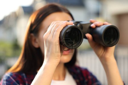 Photo for Concept of private life. Curious young woman with binoculars spying on neighbours outdoors, closeup - Royalty Free Image