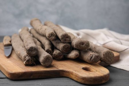 Raw salsify roots on grey wooden table, closeup