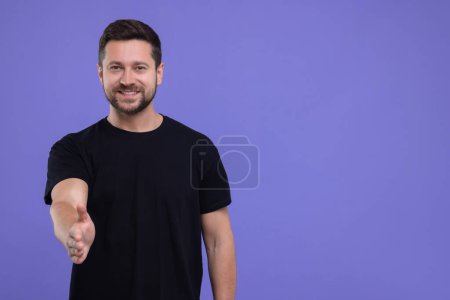 Téléchargez les photos : Homme heureux accueillant et offrant poignée de main sur fond violet. Espace pour le texte - en image libre de droit